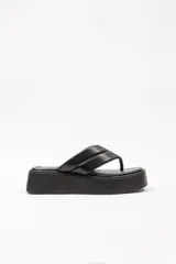Sandalias de plataforma color negro, de tipo ojota con tira ancha acolchada y suela gruesa.