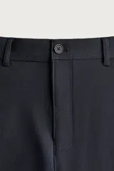 Pantalón chino negro slim fit de corte recto, con bolsillos frontales, trabillas para cinturón y cierre frontal con cremallera y botón.
