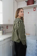 Blusa de algodón con estampado a cuadros en tonos azul y negro, con bordados decorativos en color bordó sobre el canesú. Presenta cierre frontal con botones, cuello redondo y mangas largas levemente abullonadas.