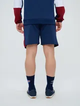 Bermuda deportiva Umbro del Club Nacional de Football, color azul marino, con cordón ajustable en la cintura, bolsillos laterales, el escudo del club en una pierna y el logo de la marca en la otra.