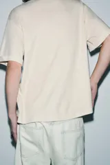 Camiseta de manga corta y cuello redondo, calce regular, color crema con textura jaspeada.