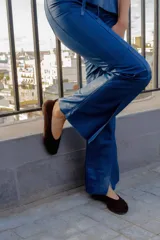 Pantalón de cuero ovino con corte flare, diseño de tiro alto y bolsillos traseros estilo jeanero. Presenta costuras verticales que estilizan la figura y tajos en el ruedo delantero.