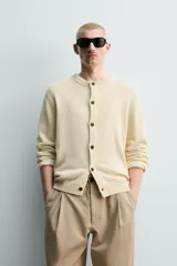 Cardigan de punto en hilatura de algodón y lino, con ajuste regular, cuello redondo, manga larga y acabados en rib. Presenta cierre frontal de botonadura con botones oscuros.