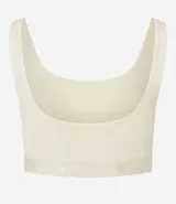 Top deportivo color blanco hueso, de corte ajustado, con breteles anchos y banda elástica inferior con inscripción. Presenta un pequeño recorte circular en el centro del busto.