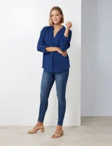 Blusa de gasa color beige, marca Floral & Ivy, con cuello a la base y escote en V. Las mangas son largas y regulables con presilla y botón.