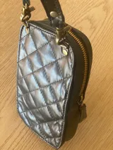 Cartera pequeña negra con diseño acolchado, cierre de cremallera y correa de mano. Incluye tarjetero interno.