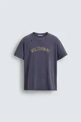Camiseta de manga corta, corte holgado, color gris oscuro o azul marino con efecto lavado y rotos. Estampado frontal con el texto "WILTONWAY" en letras doradas.