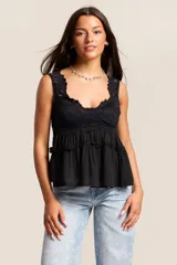 Conjunto de dos piezas color blanco, compuesto por una musculosa con escote en V con detalles de encaje y volados en el torso, y un short a juego con terminaciones de encaje calado en el ruedo.