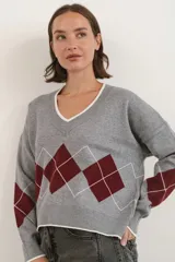 Sweater de punto con diseño de rombos en color gris, bordó y blanco. Presenta cuello en V con detalle de borde en contraste, mangas largas y puños acanalados.