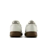 Championes New Balance modelo U5006VG, color blanco con detalles en marrón oscuro y suela marrón. Presentan el logo "N" en los laterales y cordones blancos.