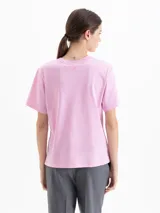 Remera de algodón con cuello redondo y mangas cortas. Presenta un diseño estampado con flores grandes en la parte superior delantera y un pequeño detalle bordado en la parte inferior.