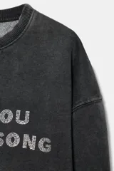 Sudadera de cuello redondo y manga larga, confeccionada en mezcla de algodón con efecto lavado. Presenta un texto estampado a contraste en la parte frontal y acabados en rib a tono.
