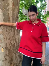 Buzo rojo de punto con cuello polo, botones blancos y mangas cortas con ribete blanco y azul marino.