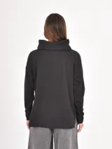 Polera de manga larga en color negro, confeccionada en tejido de punto con textura acanalada fina. Presenta un cuello alto tipo polera, corte holgado y puños ajustados.