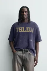 Remera de manga corta con corte relajado, confeccionada en tejido de algodón con textura tipo waffle. Presenta un efecto de lavado desgastado en color azul oscuro y estampado gráfico a contraste en el frente.