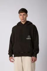 Buzo canguro oversize de algodón frizado con efecto gastado, capucha y bolsillo frontal tipo canguro. Presenta estampa gráfica sutil en el pecho.