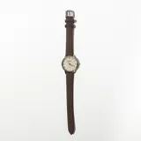 Reloj de pulsera con correa de cuero marrón y esfera redonda color crema con números arábigos y agujas doradas.