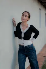 Saco tipo cardigan bicolor con diseño de bloques en blanco y negro, cuello en V, cierre frontal con botones y mangas largas con puños ajustados.