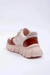 Championes deportivos para mujer, modelo Vedra de Pdk, en color beige con detalles en marrón y suela chunky tractada. Presentan tiras elásticas cruzadas en el empeine y cierre de velcro superior.