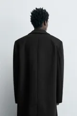 Abrigo regular fit de color negro, confeccionado con mezcla de lana y cashmere. Presenta cuello con solapas de muesca, manga larga, bolsillos de vivo en la cadera, abertura central en la espalda y cierre frontal de botonadura con tres botones.