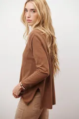 Sweater de tejido de punto color beige, con escote en V y mangas largas. Presenta un diseño básico y versátil de corte recto.