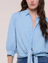 Camisa de lyocell color celeste, con cuello camisero, cierre frontal con botones y detalle de nudo en el ruedo. Presenta mangas tres cuartos abullonadas con puños elásticos.