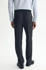 Pantalón de traje negro, de corte regular fit y silueta clásica, con bolsillos laterales y traseros ribeteados, cierre con cremallera y botón oculto.