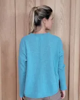 Sweater de punto color beige, con cuello en V, manga larga con puños acanalados y diseño holgado.