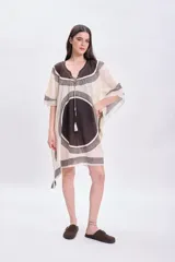 Vestido corto sin mangas color crudo, con escote en V y ajuste en el busto mediante lazos. Presenta un estampado geométrico en tonos marrones y negros.