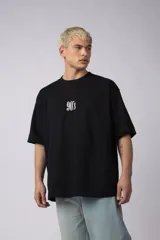 Remera negra de corte oversize confeccionada en algodón premium. Presenta un bordado frontal con la inscripción '90's' y un parche gráfico en la espalda con estética grunge.