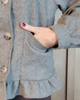 Sobrecamisa de pana color marrón oscuro, con cuello camisero, cierre frontal de botones y detalle de volado en el ruedo. Presenta mangas largas con puños y bolsillos frontales aplicados.