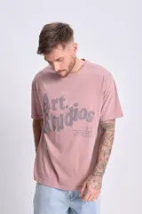 Remera manga corta oversize color rosa con estampa frontal con la leyenda "Art Studios" en gris.