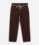 Pantalón masculino modelo baggy color marrón, confeccionado en sarga con material certificado BCI. Presenta detalles de costura contrastante, cierre tradicional y cordón blanco para lazo en la cintura.