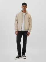 Jean de corte slim, color negro lavado, con cierre de botón y cremallera, y diseño de cinco bolsillos.