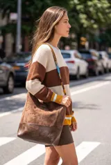 Sweater de punto oversize con diseño de franjas horizontales en tonos beige, marrón y blanco, con cuello redondo y mangas largas con puños acanalados en contraste.