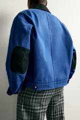 Cazadora cropped fit de algodón azul con efecto lavado, cuello solapa negro en contraste, cierre frontal con cremallera y bolsillos de plastrón con solapa en el pecho.