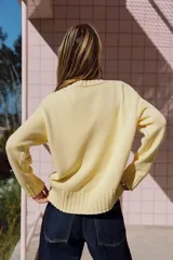 Sweater de punto color amarillo claro, con cuello redondo, manga larga y dobladillo asimétrico más largo en la parte trasera. Presenta acabados en rib en cuello, puños y ruedo.