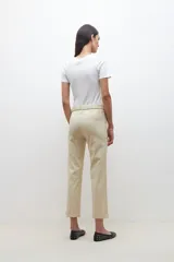 Pantalón color beige de corte recto, con cinturón de cuero sintético trenzado.