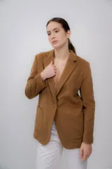 Blazer color camel de baby alpaca, con cuello de solapa, cierre frontal con botones y bolsillos laterales.