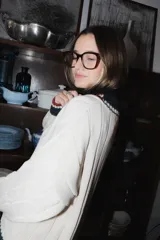 Buzo tejido de punto color terracota con diseño de rayas verticales en relieve. Presenta cuello en V con detalles de rayas en azul marino, blanco y negro, y puños acanalados a juego. Incluye un pequeño bordado en el pecho.