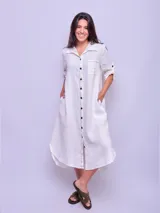 Vestido camisero largo color verde militar, confeccionado en lino, con cuello clásico, mangas largas con puños abotonados y cierre frontal con botones. Incluye un bolsillo de parche en el pecho.