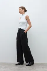 Pantalón de corte sastrero y pierna ancha, confeccionado en lyocell. Presenta pinzas en la cintura, cierre frontal con botón y bolsillos laterales. Incluye un cinturón fino de cuero con hebilla metálica.