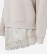 Buzo de algodón con felpa, corte oversized, cuello redondo y mangas largas. Presenta un detalle de encaje aplicado en el ruedo, aportando un contraste femenino y sofisticado.