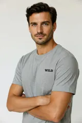Remera de algodón gris melange, de manga corta, con cuello redondo a la base y pequeño estampado con la palabra "WILD" en el pecho.