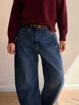 Pantalón de jean con corte balloon fit, de tiro alto y diseño holgado en las piernas. Confeccionado en denim con elastano, presenta un lavado azul clásico y cierre frontal con botón y cremallera.