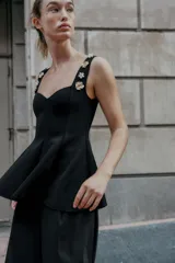 Top negro de tejido elástico, corte peplum, escote corazón y tirantes anchos decorados con aplicaciones de joyas doradas en forma de flor.