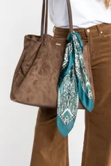 Pañuelo tipo bandana de forma cuadrada con estampado geométrico y floral en tonos verde petróleo, blanco y negro. Presenta bordes definidos y un acabado suave y ligero.