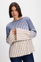 Sweater de punto con diseño de rayas verticales en dos colores, azul y crudo. Presenta cuello bote, mangas largas con terminación acampanada y un aplique decorativo en el pecho.