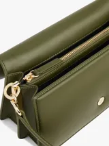Cartera tipo bandolera o de hombro color verde oliva, de acabado liso y forma rectangular. Presenta una solapa frontal con cierre magnético y un broche metálico dorado con el monograma TH. Incluye correa ajustable y herrajes dorados.
