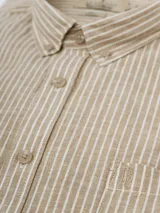 Camisa de manga larga a rayas verticales color beige y blanco, con cuello abotonado y bolsillo en el pecho. Confeccionada en lino y algodón.
